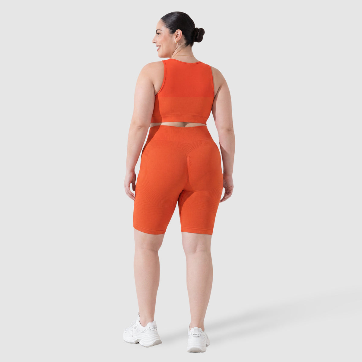 Woman wearing Sculpt 3D™ anti-cellulite shorts in orange, back view, lifted, contoured rear