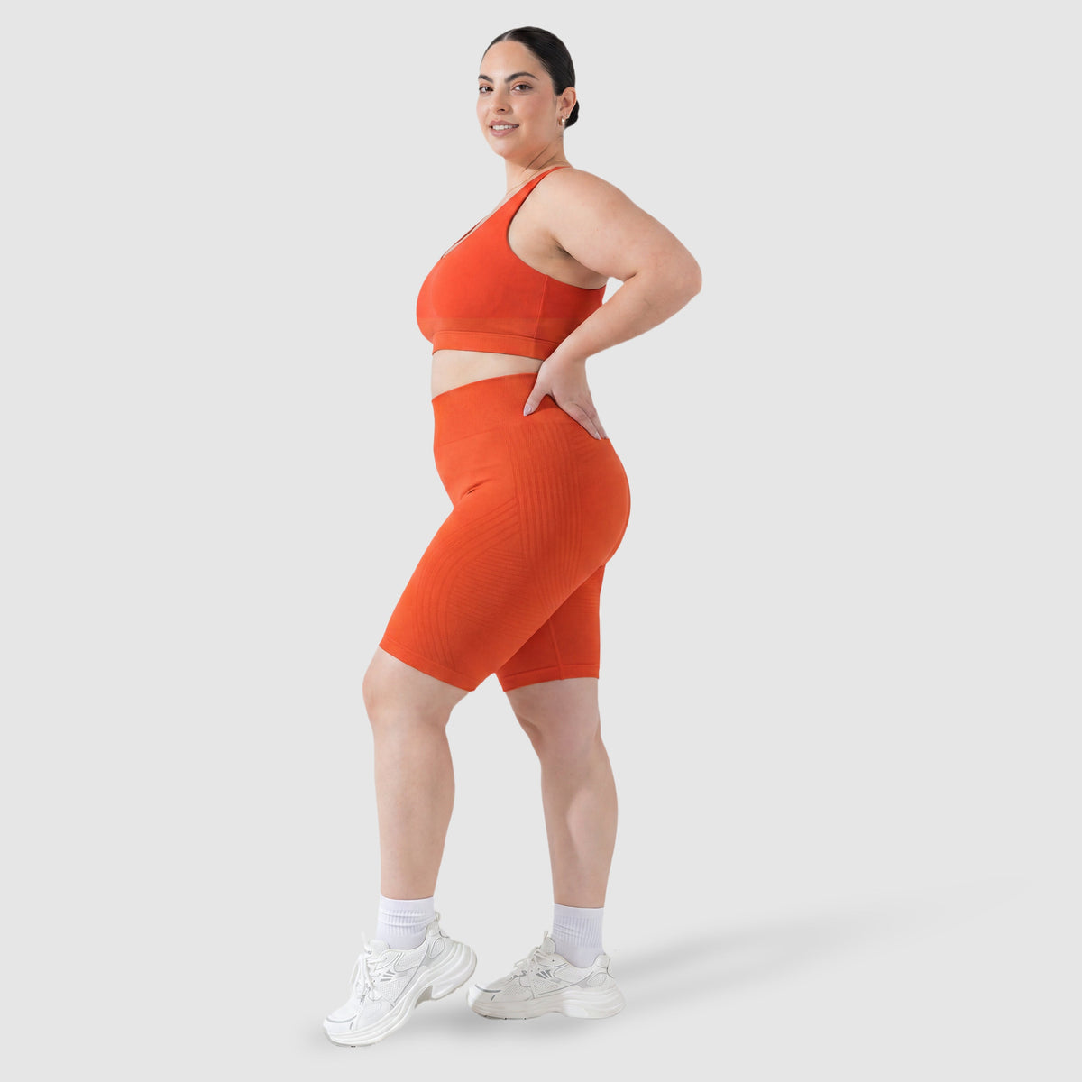 Woman wearing Sculpt 3D™ anti-cellulite shorts in orange, side view, showing the 3D sculpt lines