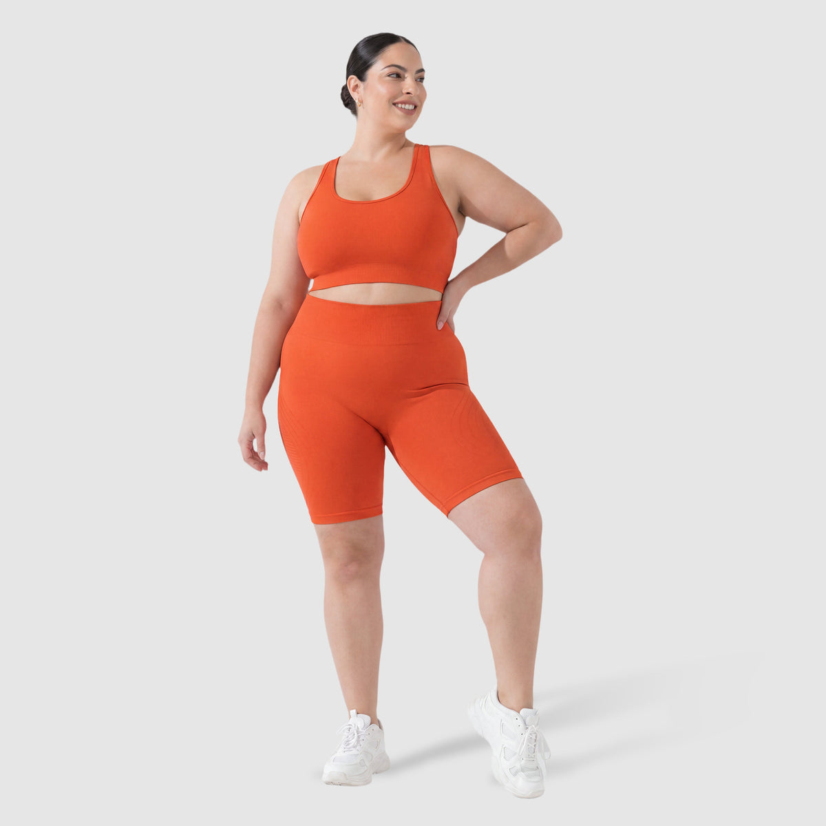 Woman wearing Sculpt 3D™ anti-cellulite shorts in orange, front view, high-waisted fit